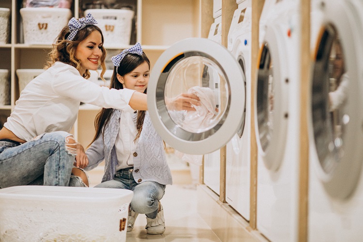 Mother with daughter doing laundry at self serviece laundrette